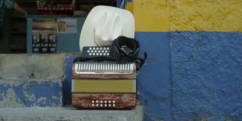 An accordion and white stetson sit on top of a cement bench