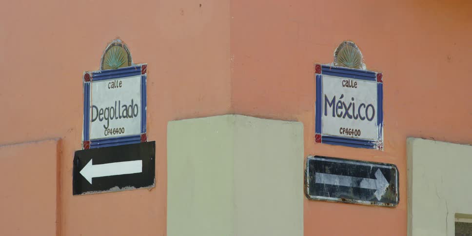 Two signs in spanish point in different directions