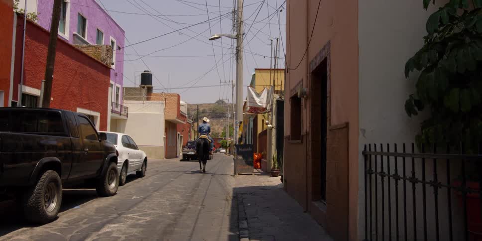 A cowboy rides a horse on a town street