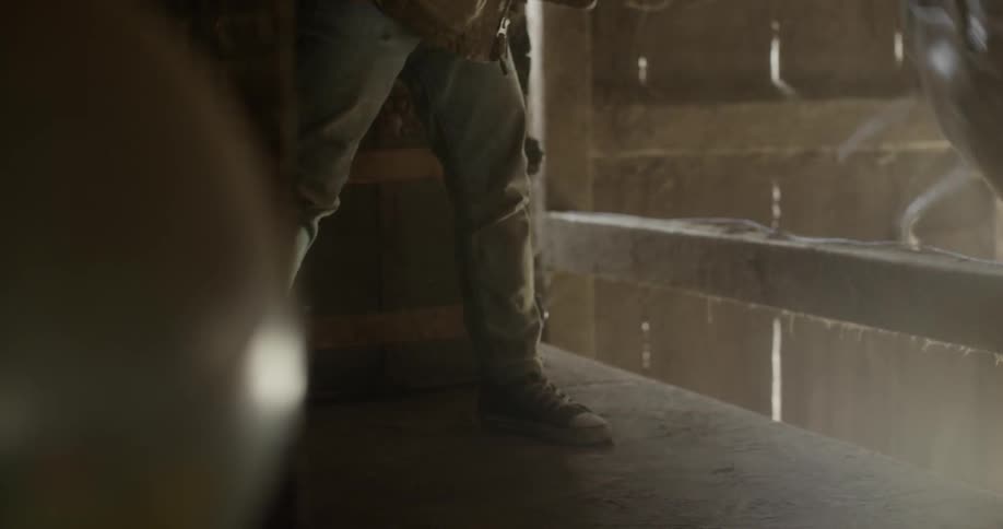A boy picking up a satchel and throwing it down from a loft
