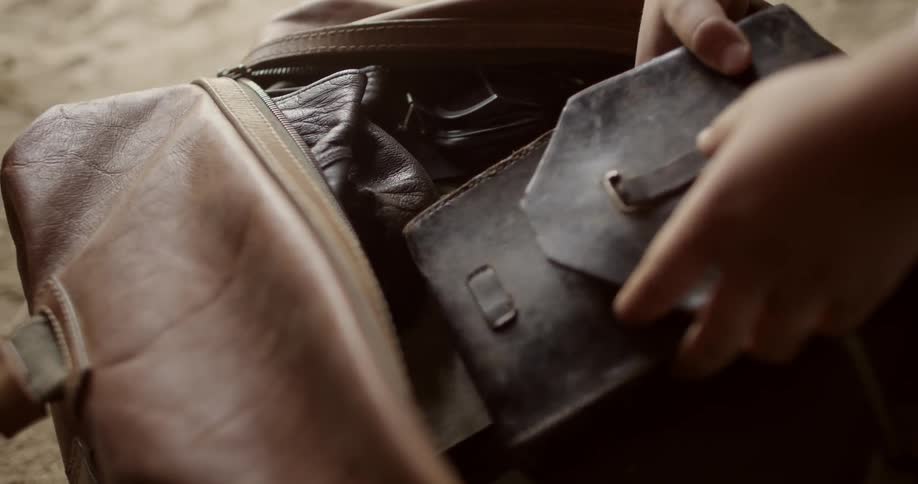 Person unzips a bag and examines the items inside