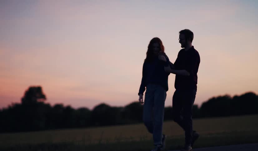 A couple walking on a path at sunset