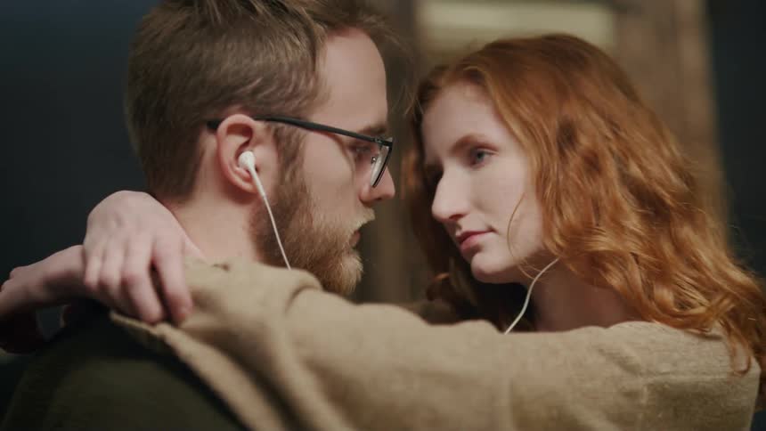 A couple dancing while listening to music through shared earphones