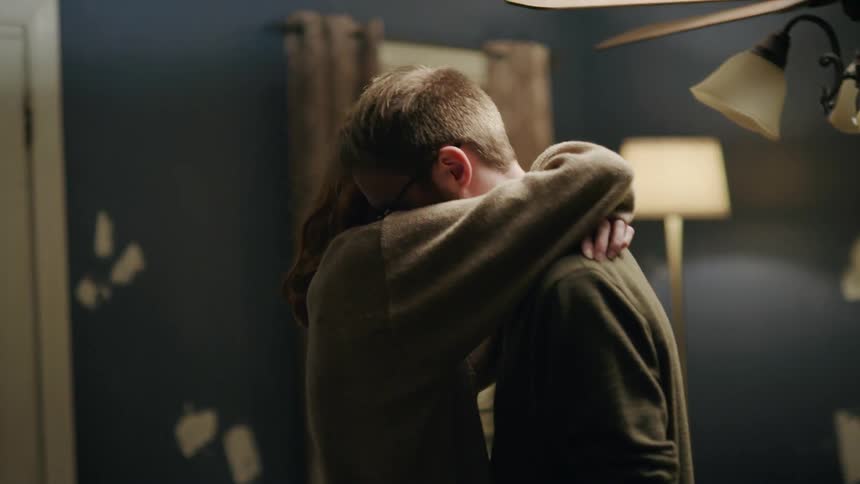 Two people hug one another near the doorway