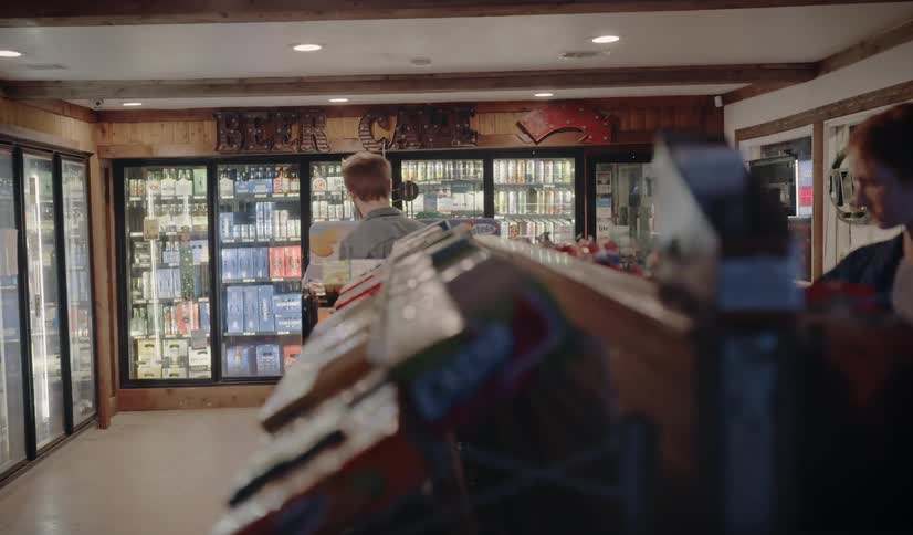 Man and woman looking through the aisles of a convenience store and grabbing snacks