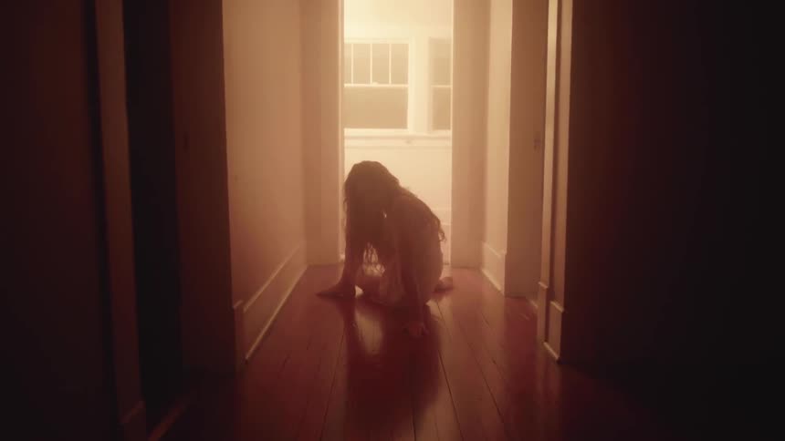 A woman in nightgown dances in a hallway at night