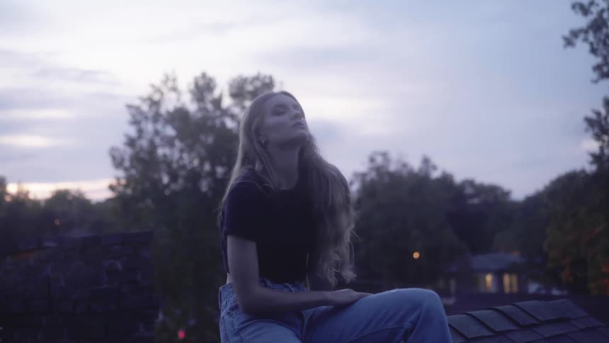 A woman sits on the ridge of a house roof