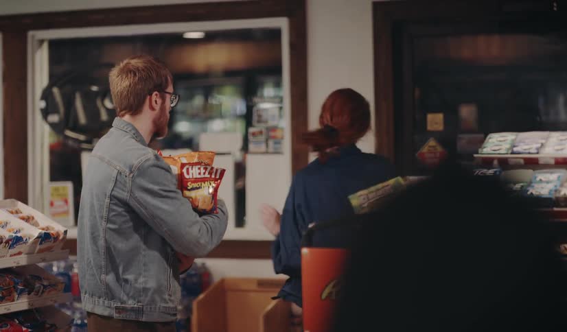 A woman loading up a mans arms with snacks
