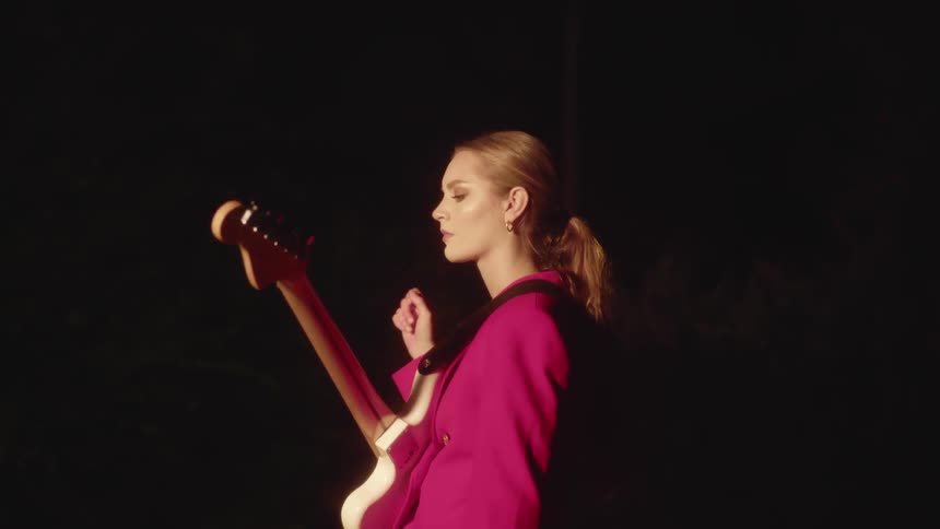 A woman with a guitar is swaying back and forth