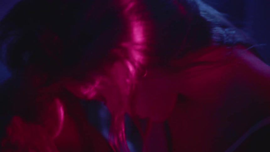 A woman sits and rocks back and forth in the dark