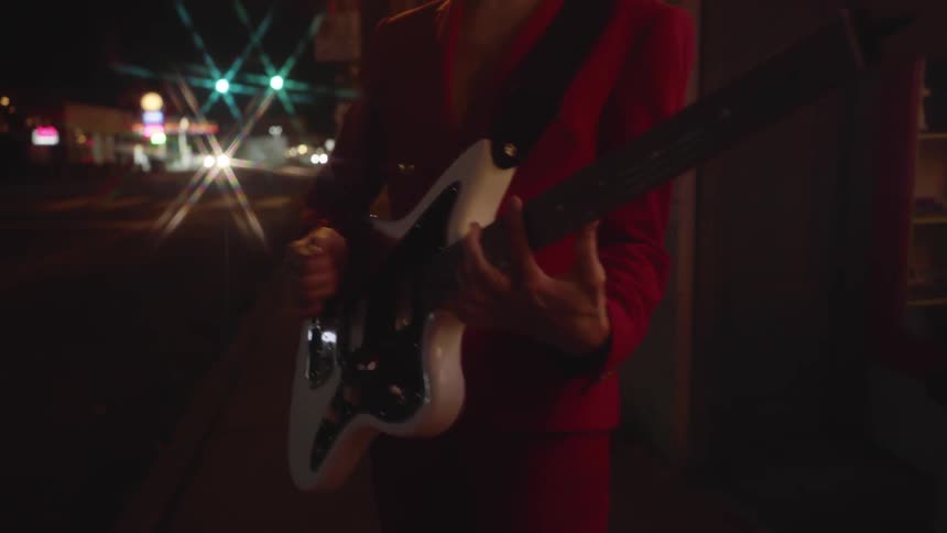 A woman playing guitar on the street at night