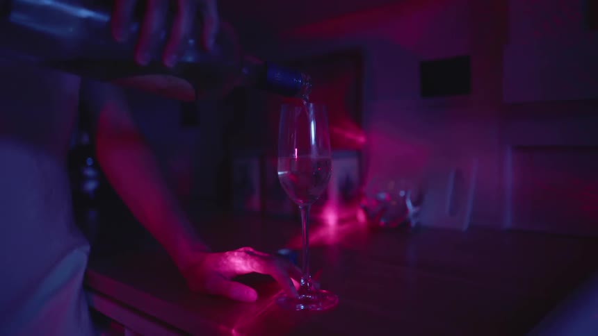 A person pours a glass of alcohol