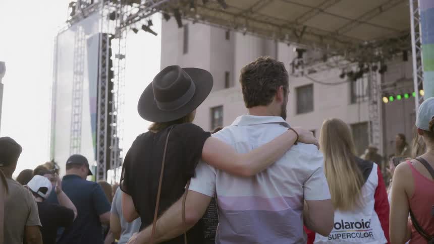 A man and woman hug while in a crowd at a concert