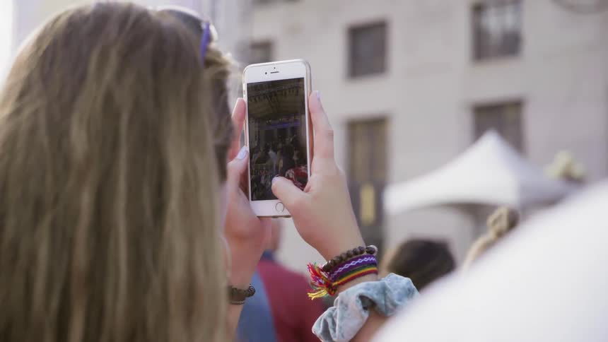 Girl recording a band on phone at an outdoor event