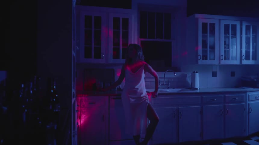 Woman holds a wine glass at night while red lights play over her