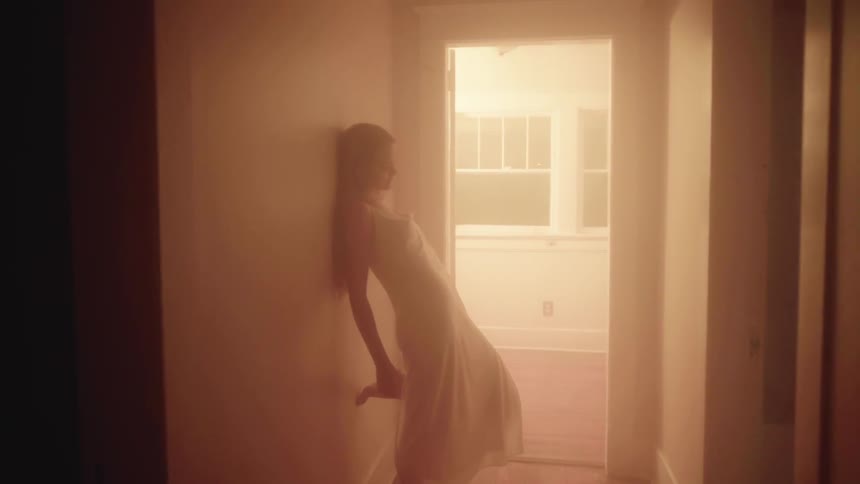 A woman leans on the wall while rubbing her back
