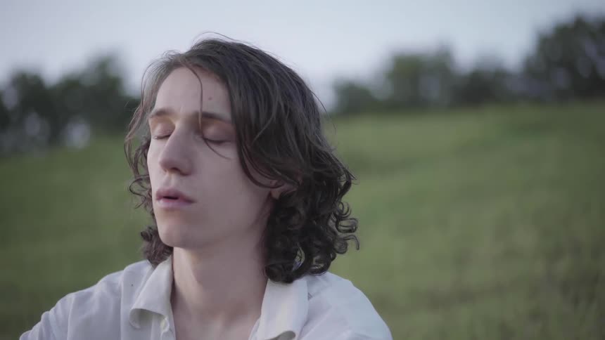 A man sits outside meditating and taking deep breaths