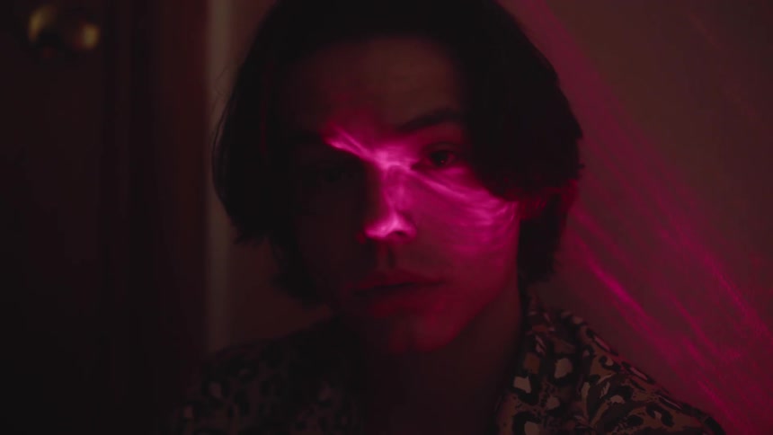 A man sitting and staring with flashing lights illuminating his face