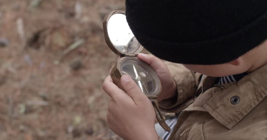A boy looks curiously at an old compass he's holding