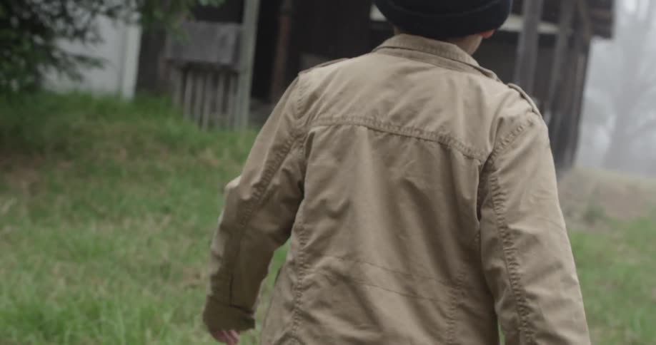 Person walks quickly to an old abandoned house