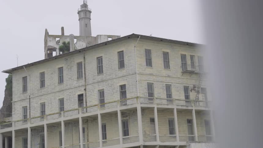 A lighthouse tower is visible behind a large building on a cloudy day