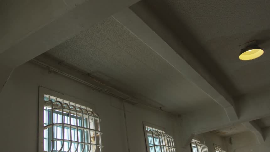 The interior of a room with metal bars on windows and beams across the ceiling
