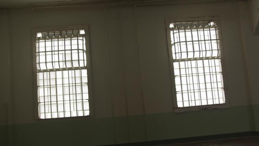 The inside of an empty rooms that has bars on the windows