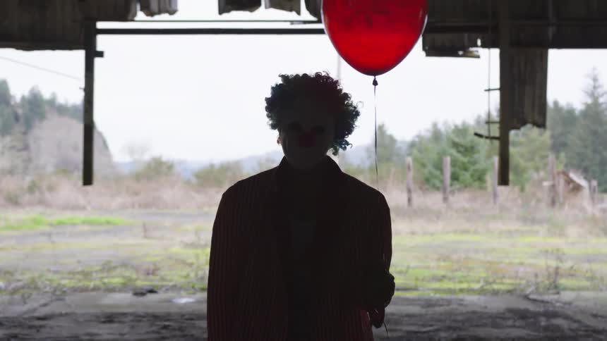 A man holds a red balloon outside