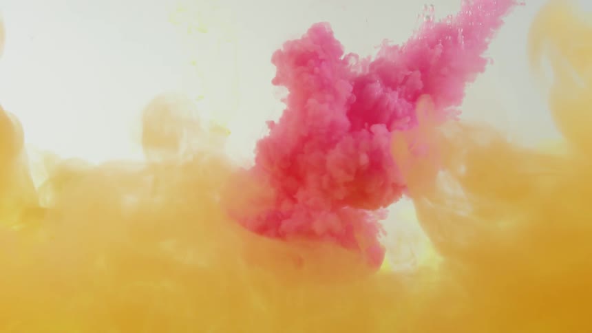 Red paint being shot into water with yellow color at the bottom