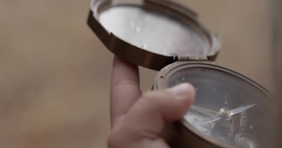 A man's hands seen opening an old fashioned compass outdoors
