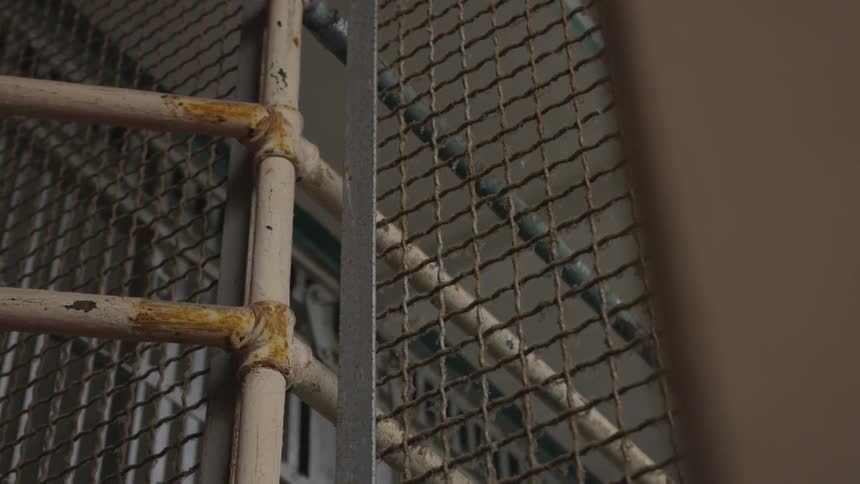A gated prison with rusty and paint chipped poles