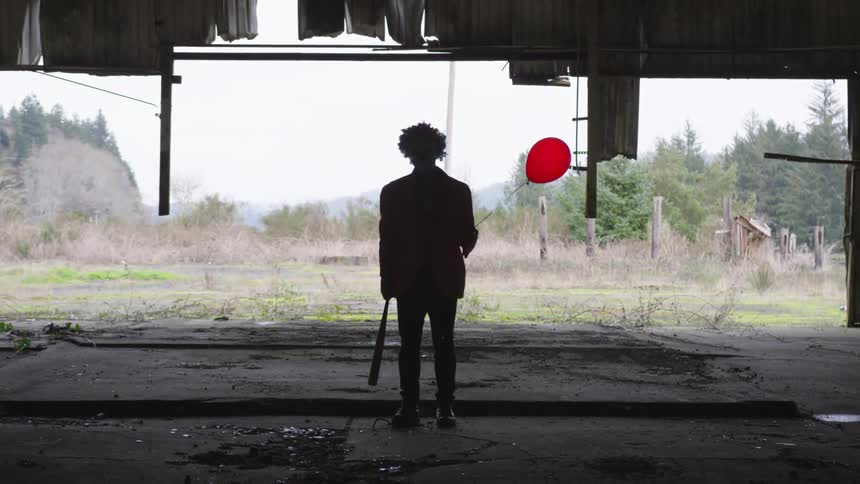 A shadow of a person holding a red balloon and bat