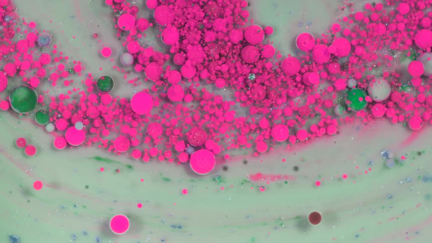 Pink green and blue circles turn and are contorted or popped on a gray backdrop