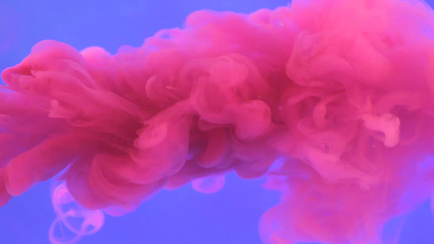 Paint being poured into liquid creating a pink cloud