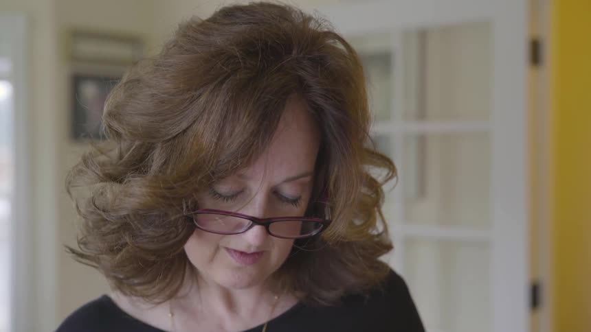 A woman wearing glasses is looking down