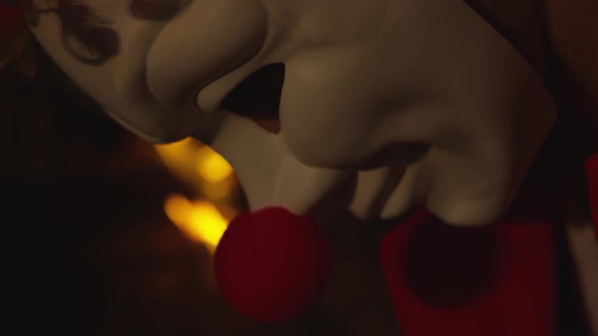 Mask with big red nose looking down near a fire
