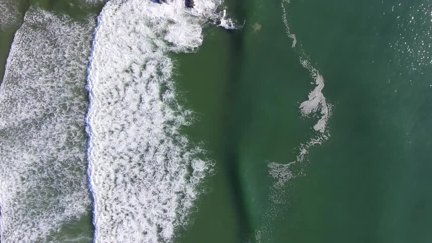 Waves rhythmically flow towards a beach