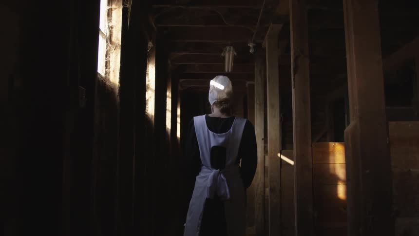 A woman walks through the hall of the barn