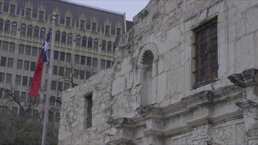 A building that has many cracks has a flag in front