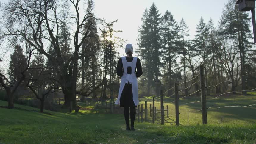 A woman standing in a yard looking at trees