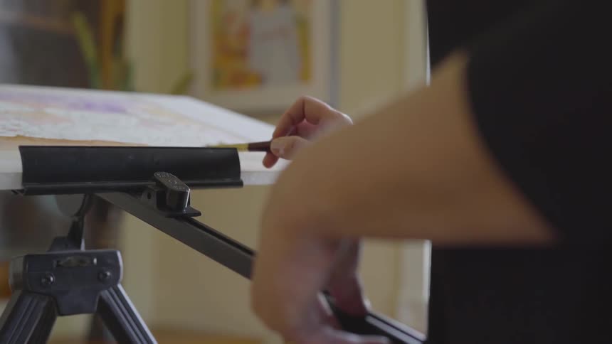 Person sketches on a piece of paper on an easel
