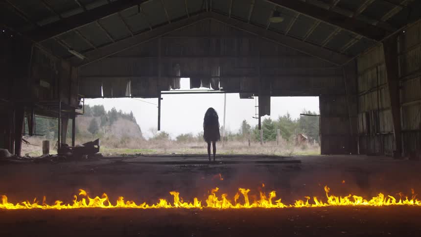 Silhouette of girl stands behind a fire line inside the building
