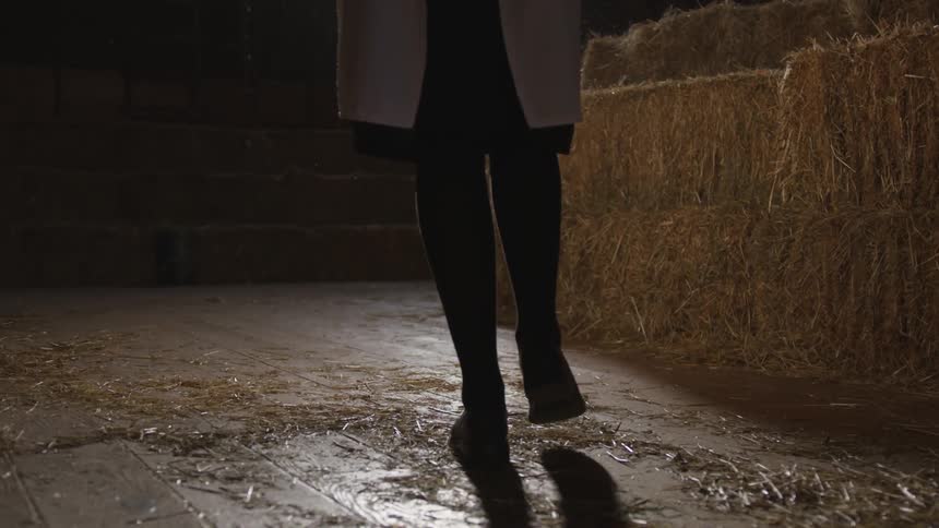 Woman walks next to bales of hay