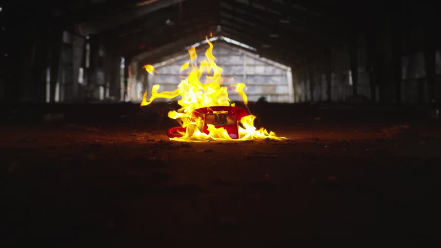 A push button red phone burning outside of a building