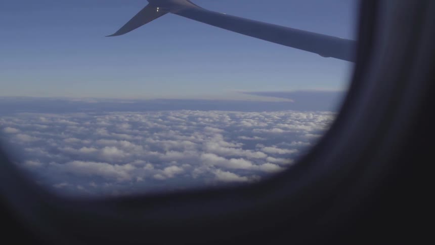 An airplane soars through the sky above the clouds