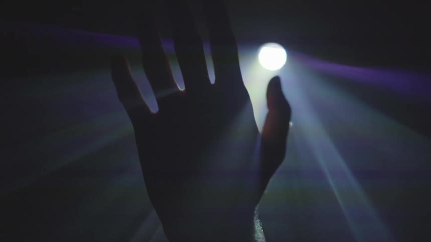 A hand in front of a colorful light