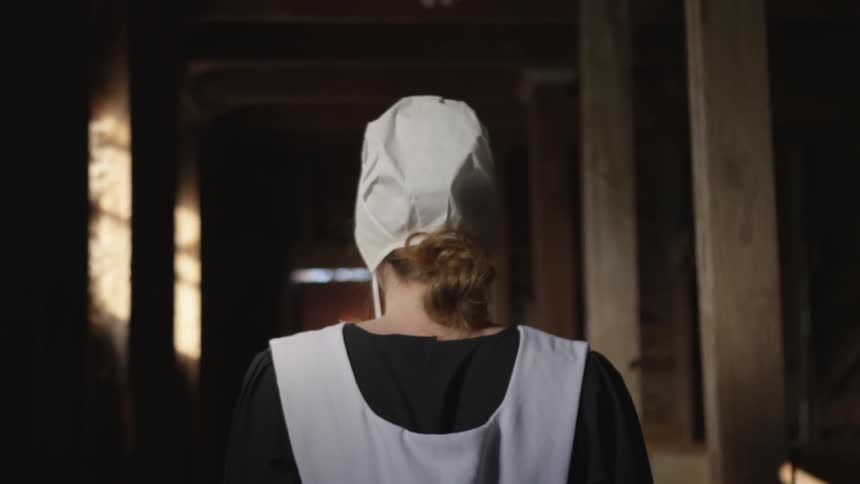 A woman walks down the dark hall