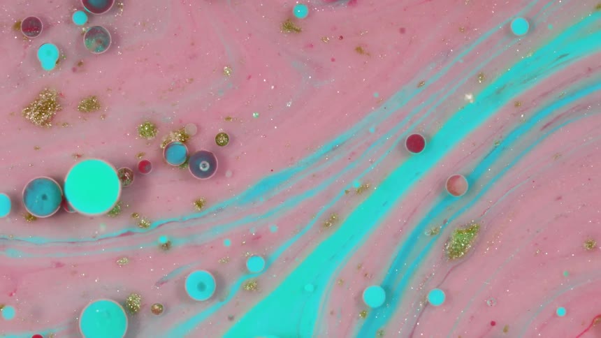 Pink liquid with teal paint and multicolored glitter and drops