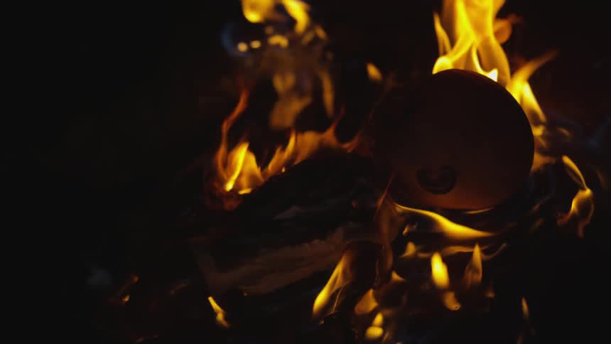 A baby doll in the dark on fire surrounded by flames