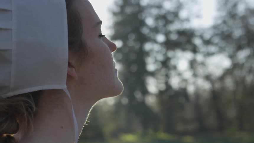A woman has her eyes closed as she sits in the forest